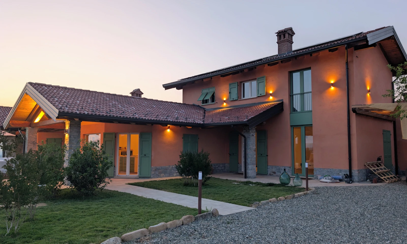 Edificio residenziale con porticato e coperture in legno, fotografato al crepuscolo.